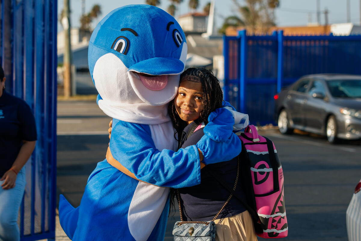 a seventh grader hugs a person in a dolphin costume