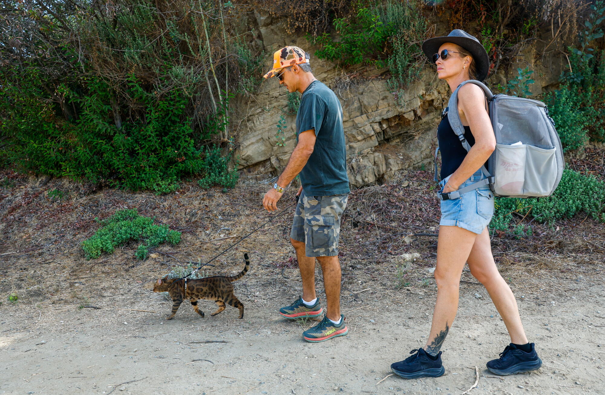 David Atrakchi and Sophie Meister walk their 3-year-old Bengal cat Taita on a trail near Hollywood Reservoir.