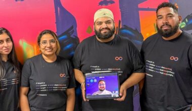 a tech company team consisting of two women and two men, plus a man's face on a tablet