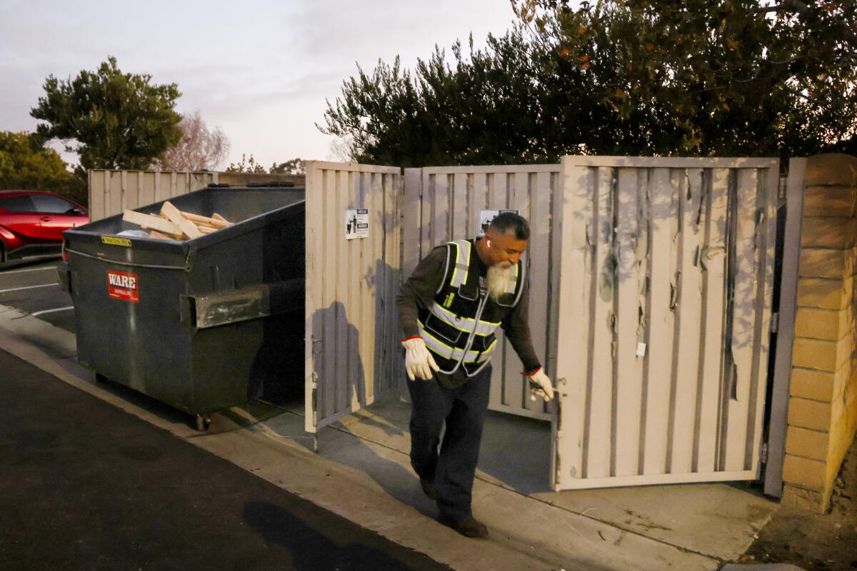 Salomon Olea opens the gate to where the trash bins are