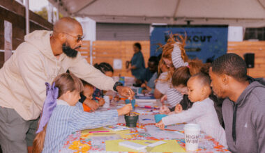 Parents and small children sit around a table and work on crafts.