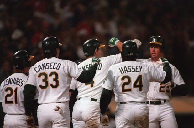 Oakland Athletics first baseman Mark McGwire, far right, bashes forearms with Jose Canseco (33), Carney Lansford and Ron Hassey (44), who scored ahead of him after his grand slam in the eighth inning against the California Angels at Oakland, Ca., on Aug. 12, 1988. It is McGwire's 21st homer of the season and the first grand slam of his major league career. The A's beat the Angels, 7-2. (AP Photo/Sal Veder)