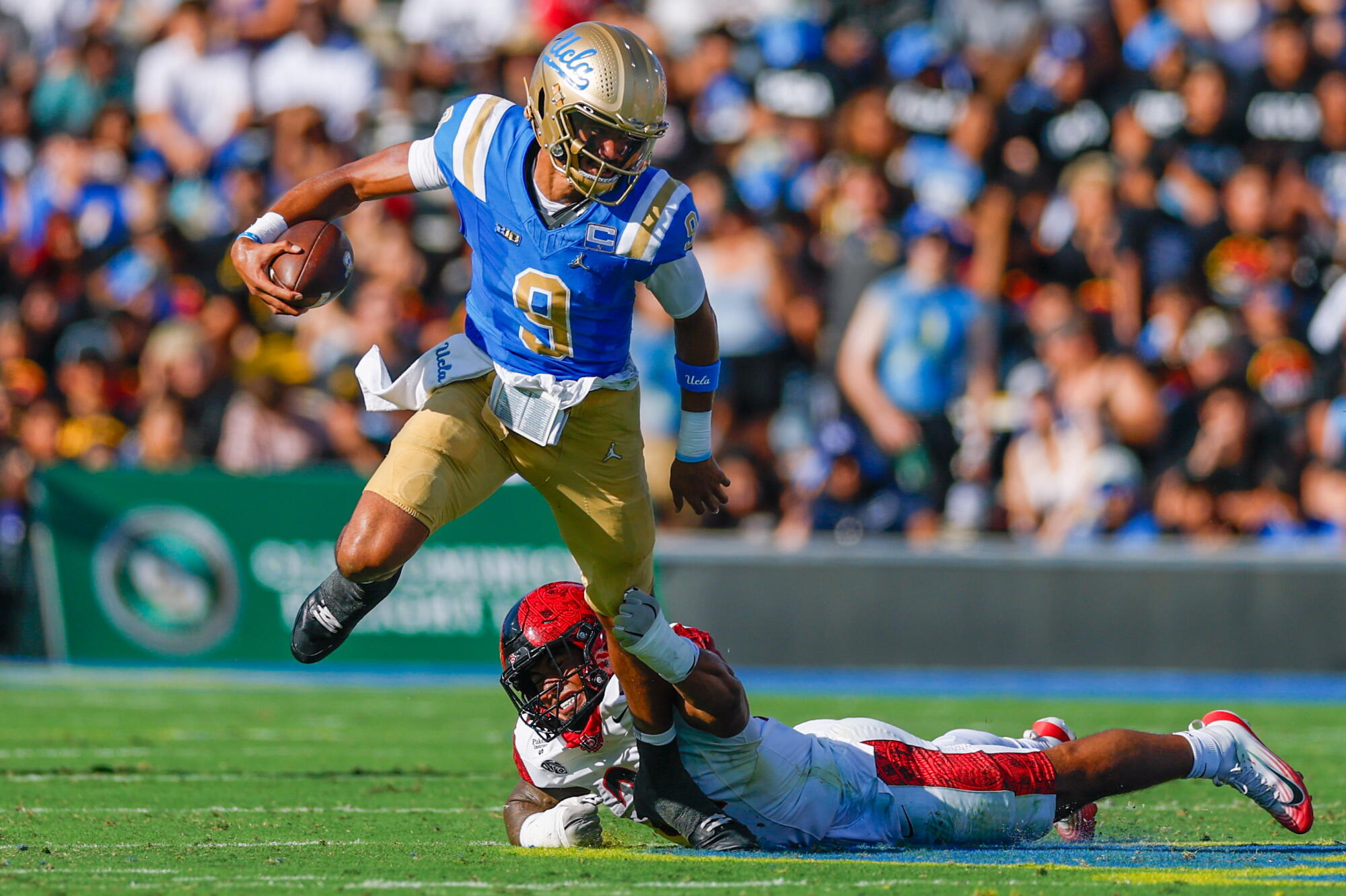 UCLA quarterback Nico Iamaleava attempts to break free from a tackle by San Diego State linebacker Tano Letuli.