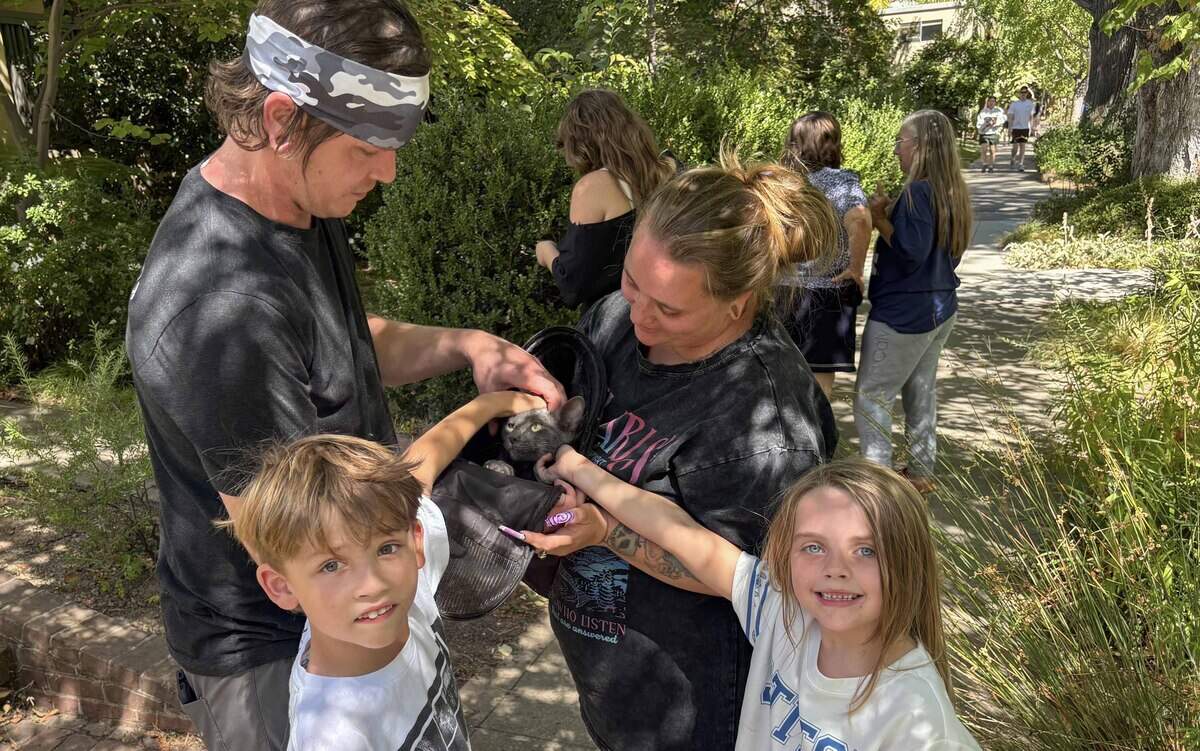 Alisha Wiborn, her husband Ronnie Barnes and their children Everett Barnes, 9, and Penelope Barnes, 7, spend time with their cat Cinder after he was rescued in Sacramento’s Boulevard Park neighborhood on Saturday.