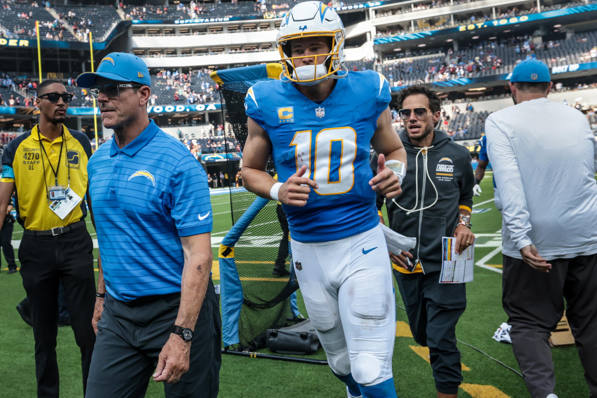 Chargers coach Jim Harbaugh, left, quarterback Justin Herbert and offensive coordinator Mike McDaniel leave the field.