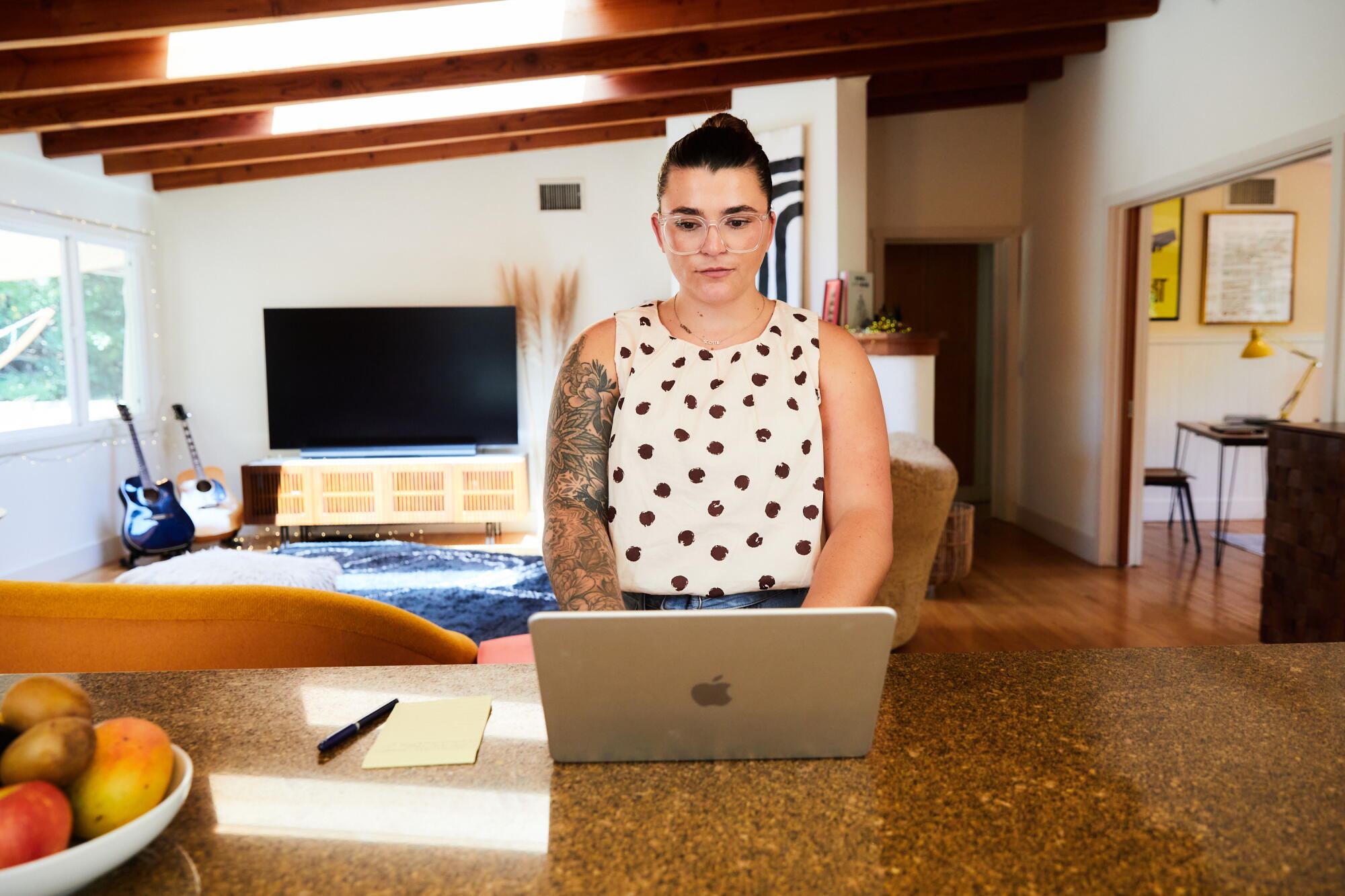 A woman types on a computer on a kitchen island.