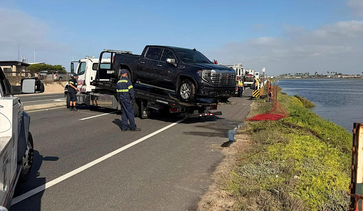 A truck is pulled Saturday from the waters off PCH south of Warner Avenue.