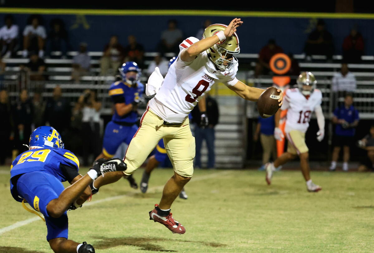 JSerra High quarterback Hayes Cloutier leaps as he tries to evade a tackle by a Bishop Amat defenders.