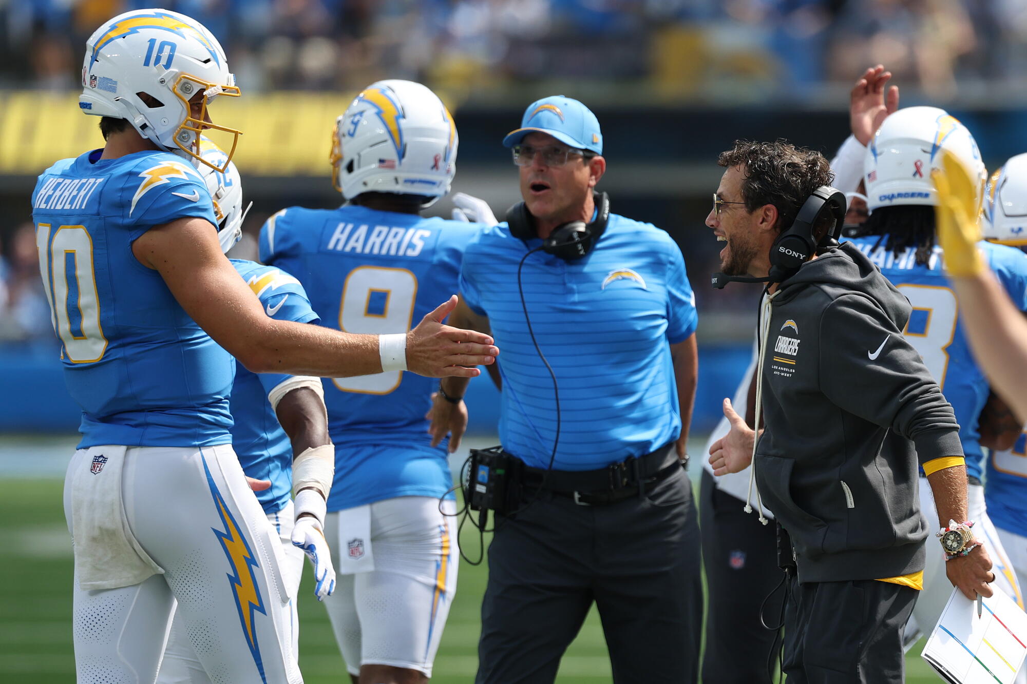 Chargers quarterback Justin Herbert celebrates with coach Jim Harbaugh, center, and Mike McDaniel after a touchdown.