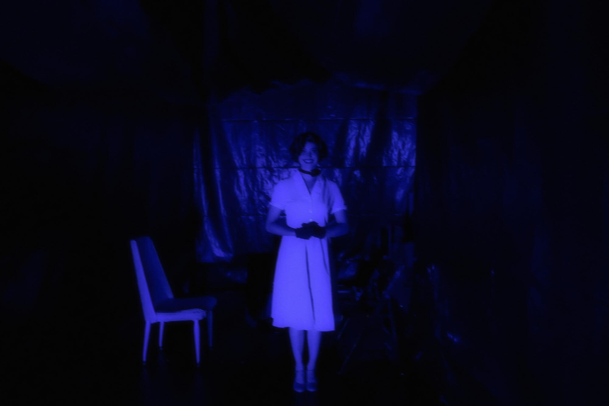 A blurry woman in a dress shrouded in blue light. 