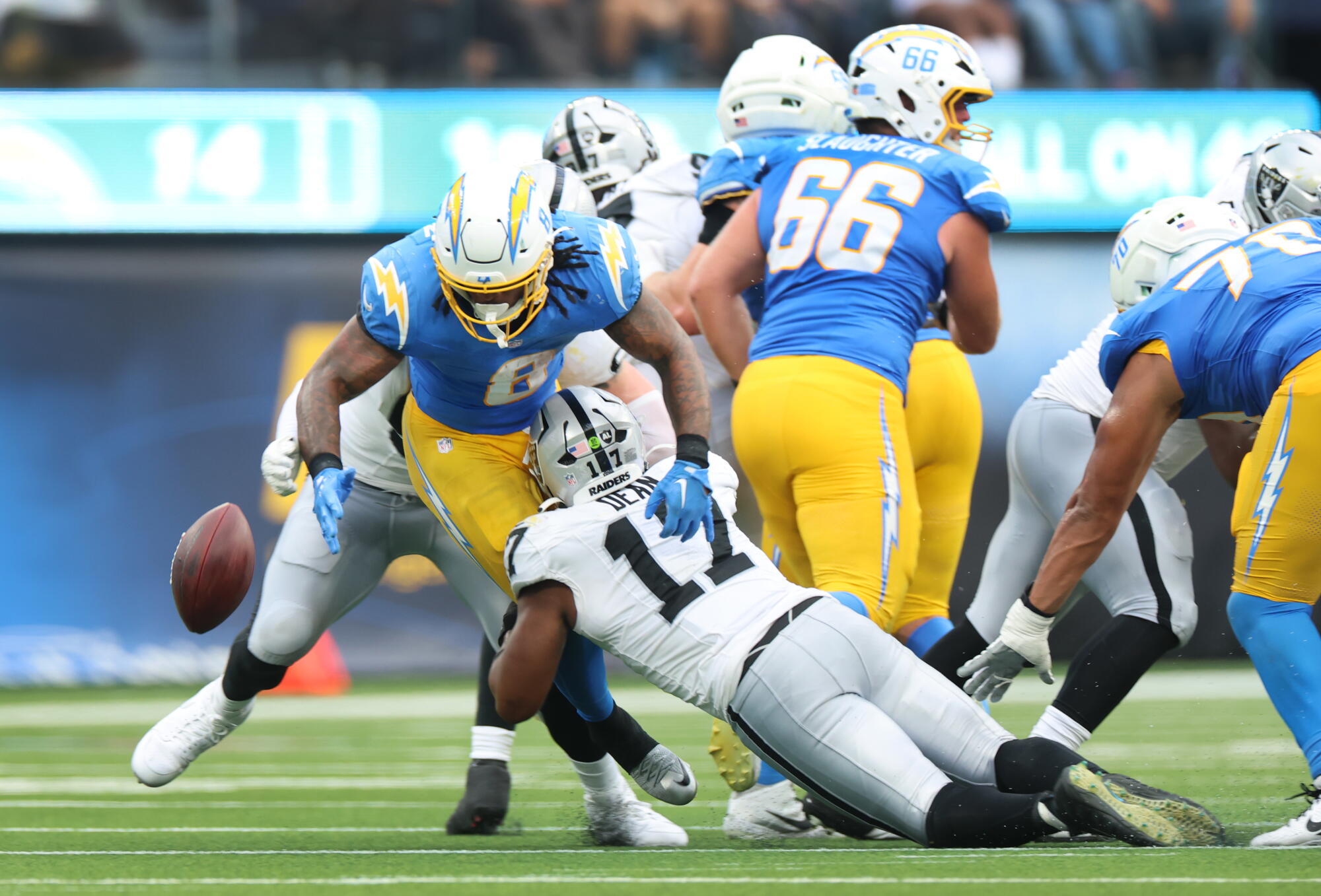 Chargers running back Omarion Hampton, left, fumbles the ball as he is hit by Raiders linebacker Nakobe Dean.