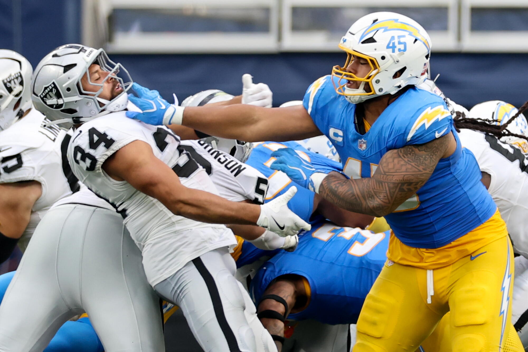 Raiders fullback Connor Heyward, left, and Chargers linebacker Tuli Tuipulotu battle during the fourth quarter Sunday.