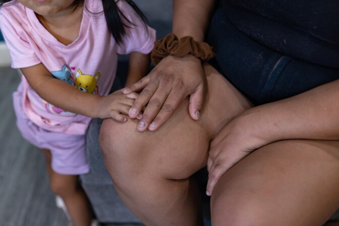A close up of a woman holding a child's hand on her lap.