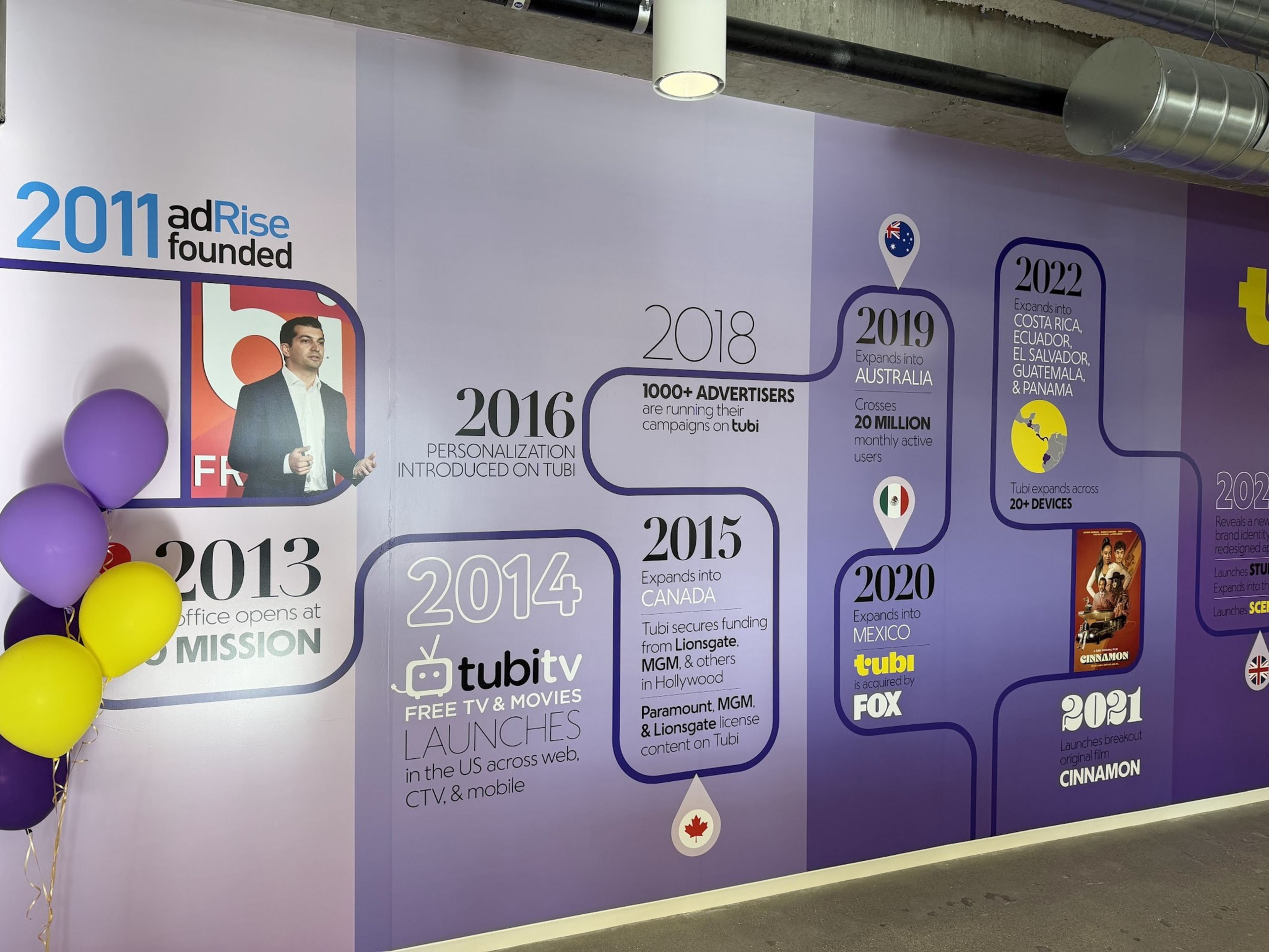 A timeline on a wall shows adRise’s milestones from 2011 founding, to Tubi TV launch in 2014, expansions to Canada, Australia, Mexico, and Latin America by 2022.