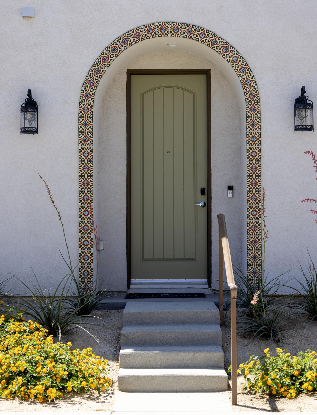 A front door with steps, tiles and flowers.