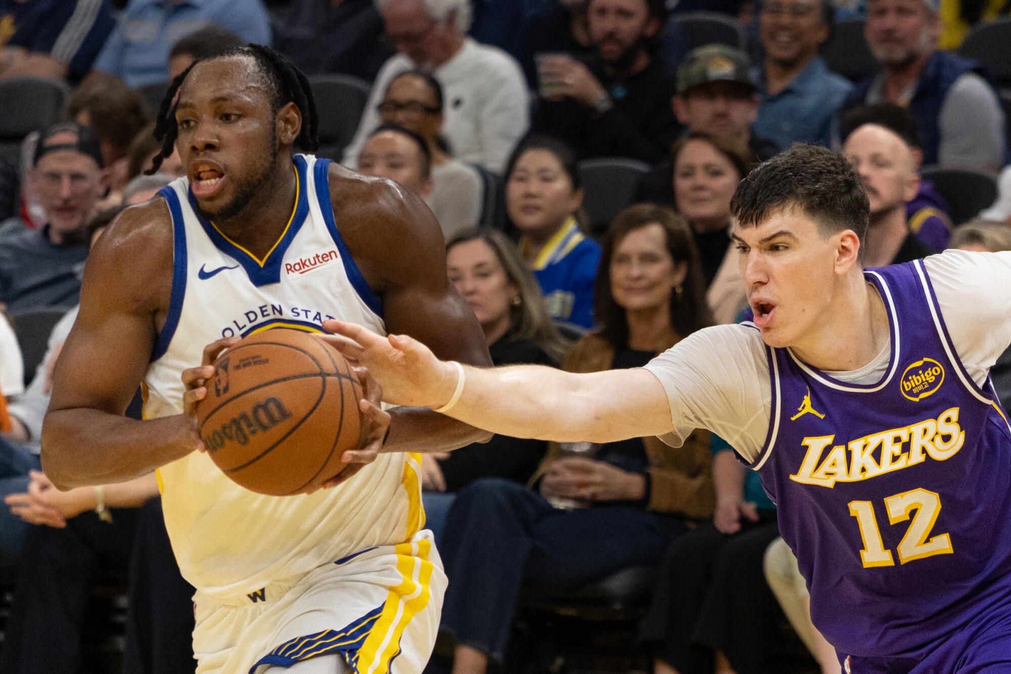 Lakers forward Jake LaRavia, right, reaches with his right hand to try to strip the ball from Warriors forward Chales Bassey.