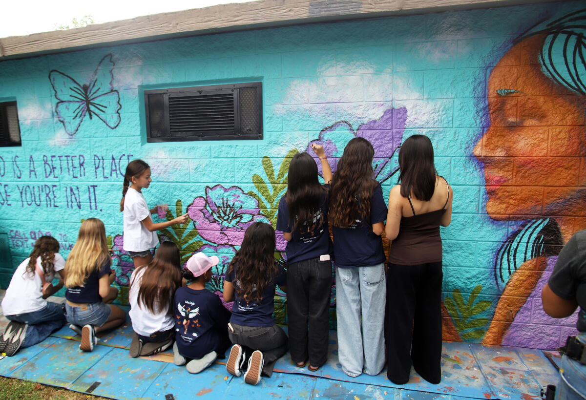 Friends and supporters of Mia Mejia take part in painting a mural in her memory. 