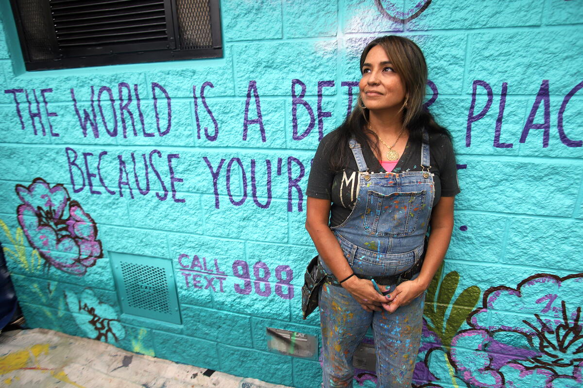 Carla Roque poses with a mural in Anaheim she designed for Suicide Prevention Month.