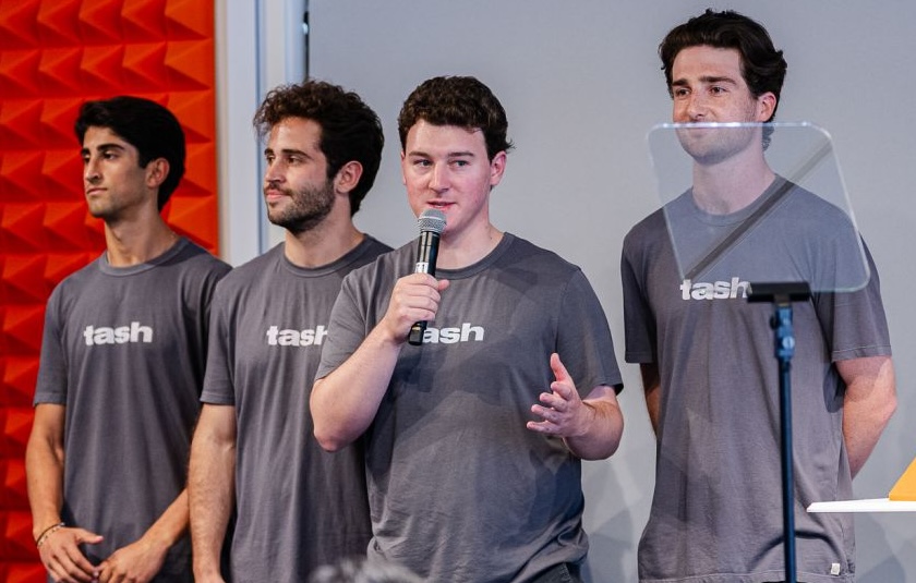 four students wearing tash t-shirts at an event