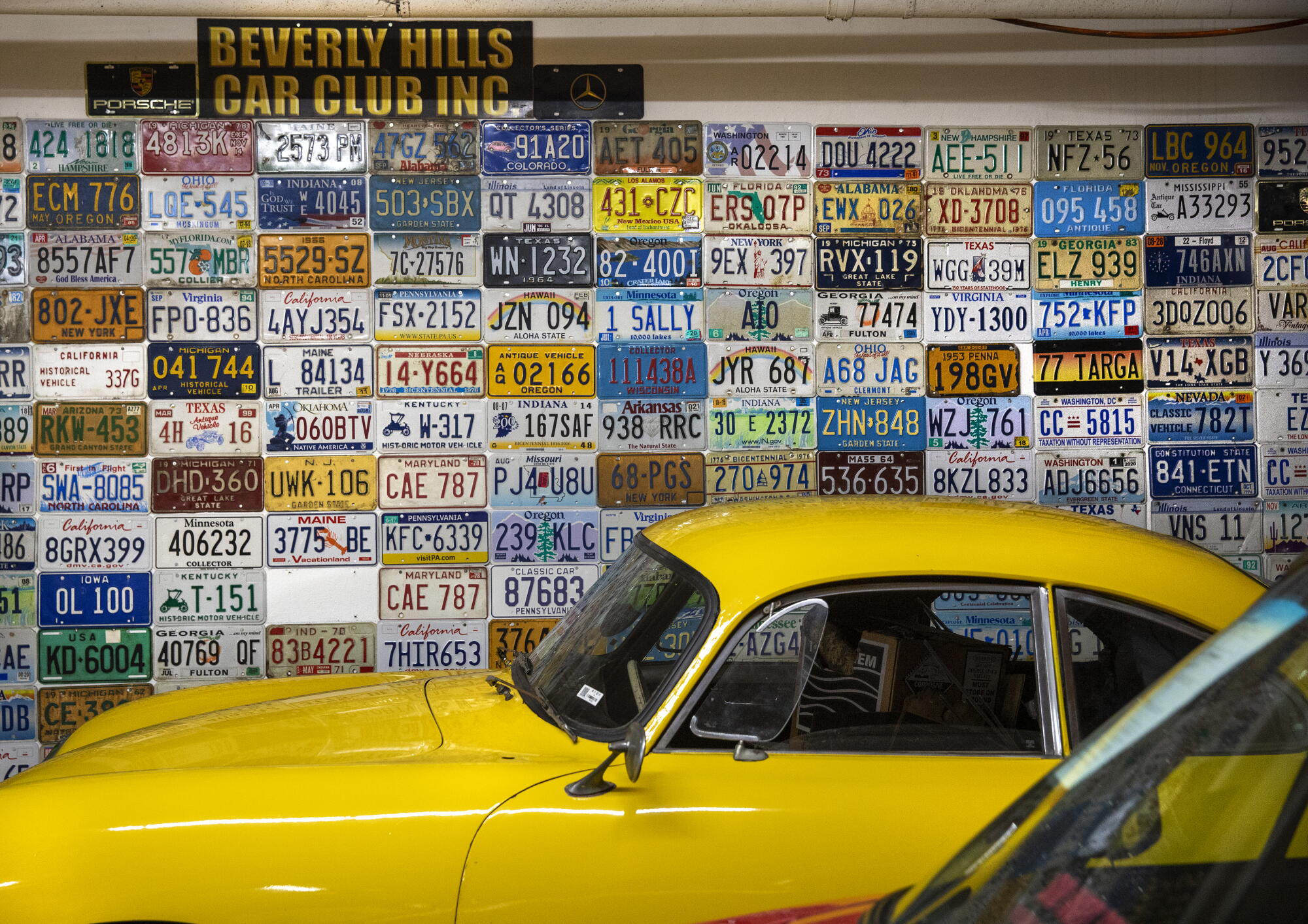 License plates from across the United States adorn a wall inside the classic car dealership Beverly Hills Car Club. 