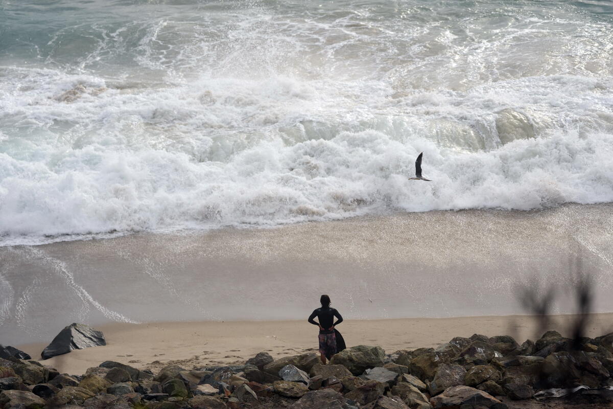 A bodyboarder watches the surf at Aliso Beach in Laguna Beach on Sunday.