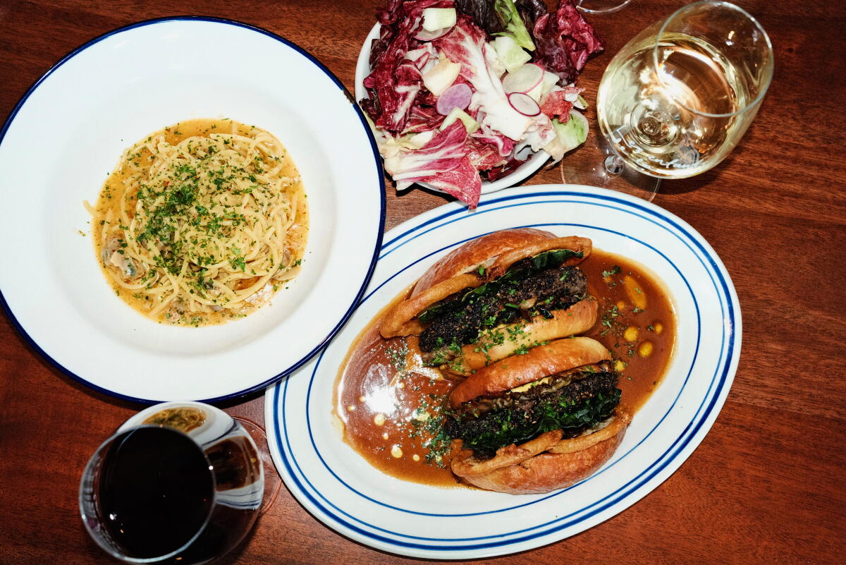 Spaghetti vongole, left, with chicory salad and hamburger au poivre topped with mushroom and fried onion 