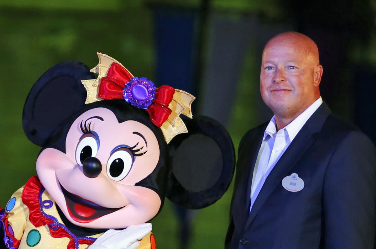 A suited executive standing with Minnie Mouse. 