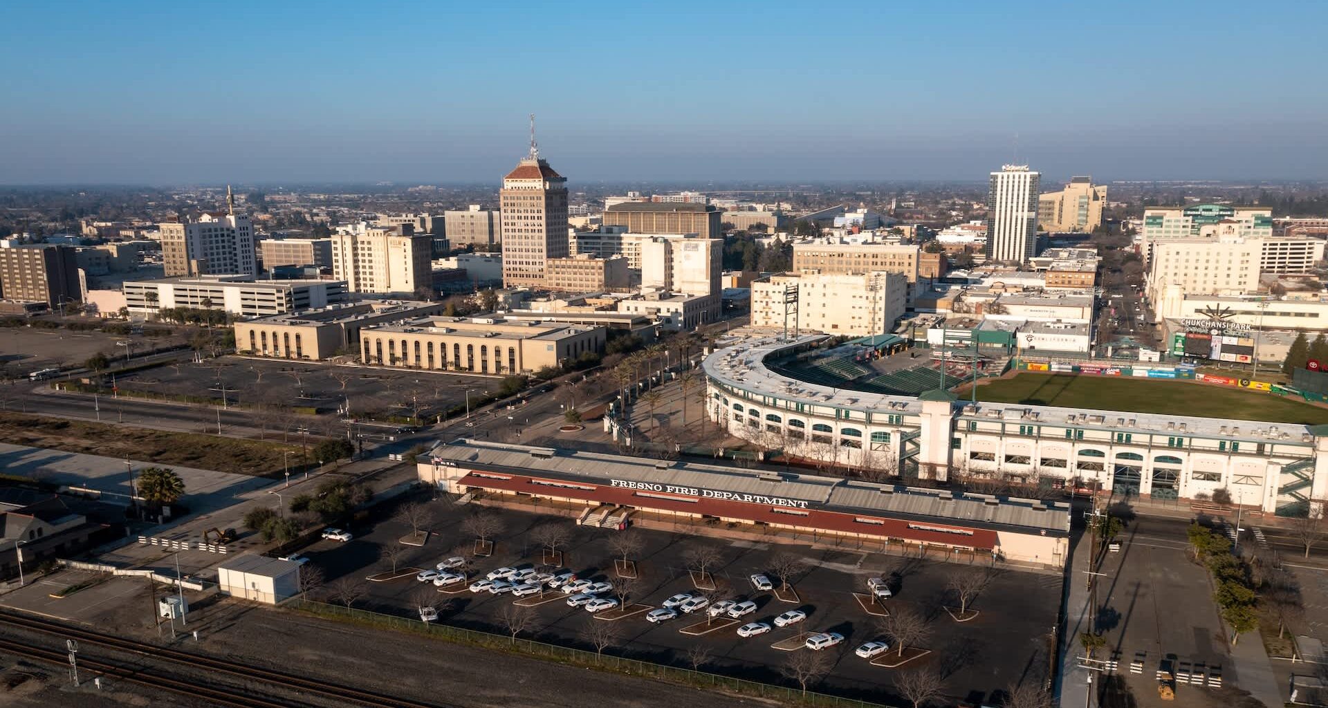 Aerial view of downtown Fresno with buildings, parking lots, and a baseball stadium.