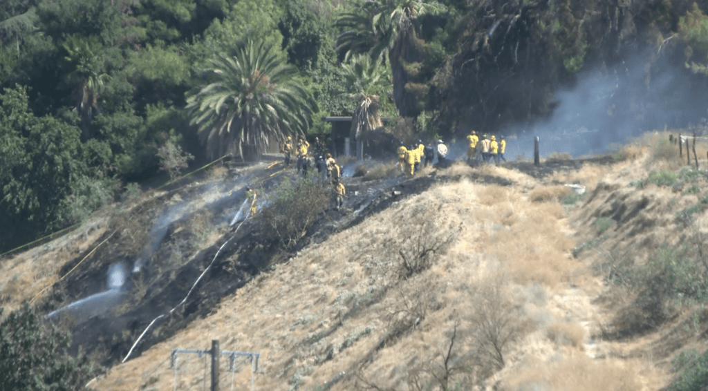 Firefighters extinguishing a fire on a hillside after a plane crash in Fresno.