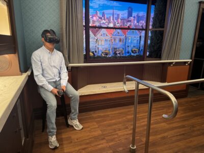 Person wearing a VR headset sits inside the Shake House at the California Academy of Sciences.