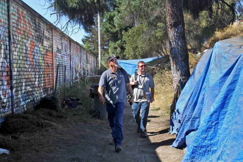 Tim Healy, center, a homeless outreach worker for the Homeless Veterans Rehabilitation Program, works with Corey Friccero, right, a veteran outreach social worker for Goodwill Veteran Family Services as they walk around a homeless encampment near the Los Gatos Creek trail in San Jose in hopes of finding veterans they can talk to about the six-month program, which provides housing, substance and alcohol treatment, life skills training, therapy and job placement.  Photo by Veronica Weber.