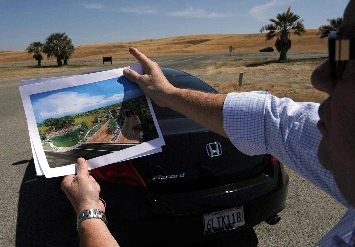 Dennis Bacopulos, a developer proposing the 2,500-home Friant Ranch development in the foothills just south of the town of Friant, holds an artist’s rendering in this 2012 file photo as he stands at the entrance of Lost Lake Park and points out how the development will appear in the hills across Friant Road.