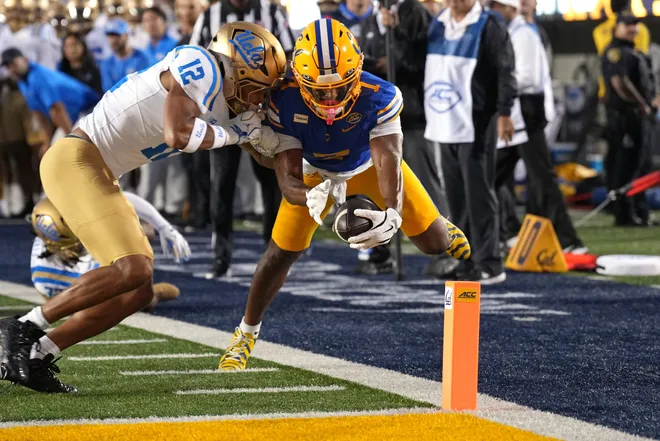 Sep 5, 2026; Berkeley, California, USA; California Golden Bears wide receiver Chase Hendricks (center) extends the ball out against UCLA Bruins defensive back Malik Hartford (12) to score a touchdown during the first quarter at California Memorial Stadium. Mandatory Credit: Darren Yamashita-Imagn Images
