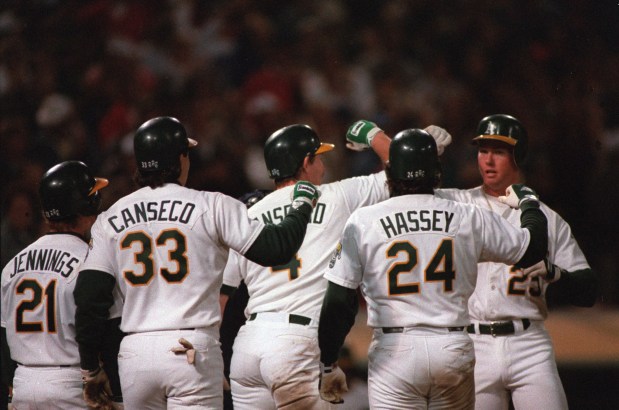 Oakland Athletics first baseman Mark McGwire, far right, bashes forearms with Jose Canseco (33), Carney Lansford and Ron Hassey (44), who scored ahead of him after his grand slam in the eighth inning against the California Angels at Oakland, Ca., on Aug. 12, 1988. It is McGwire's 21st homer of the season and the first grand slam of his major league career. The A's beat the Angels, 7-2. (AP Photo/Sal Veder)