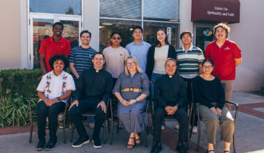 12 leaders and students from Center for Spirituality and Faith posing in front of CSF office