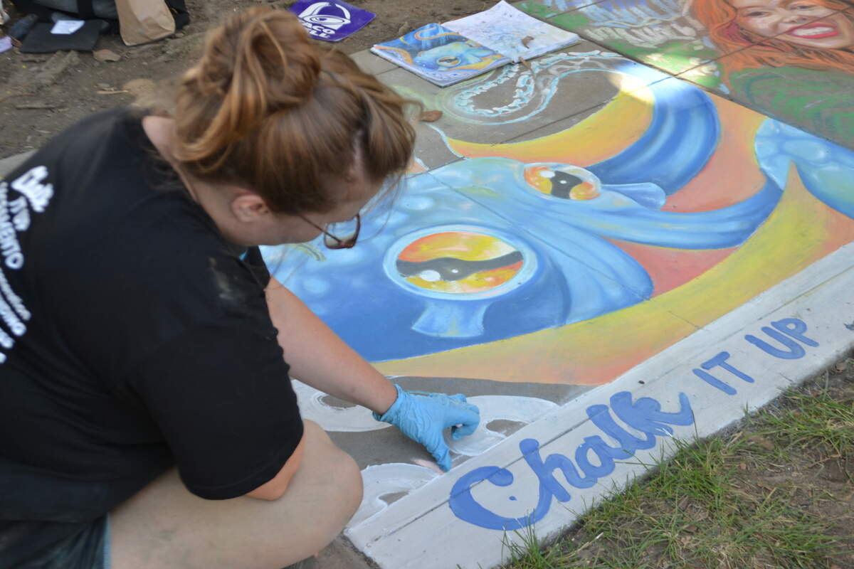 Artist Jennifer Bailey, works on her mural of a blue and orange octopus, at the annual “Chalk It Up” chalk art and music festival Saturday at Fremont Park in Sacramento.