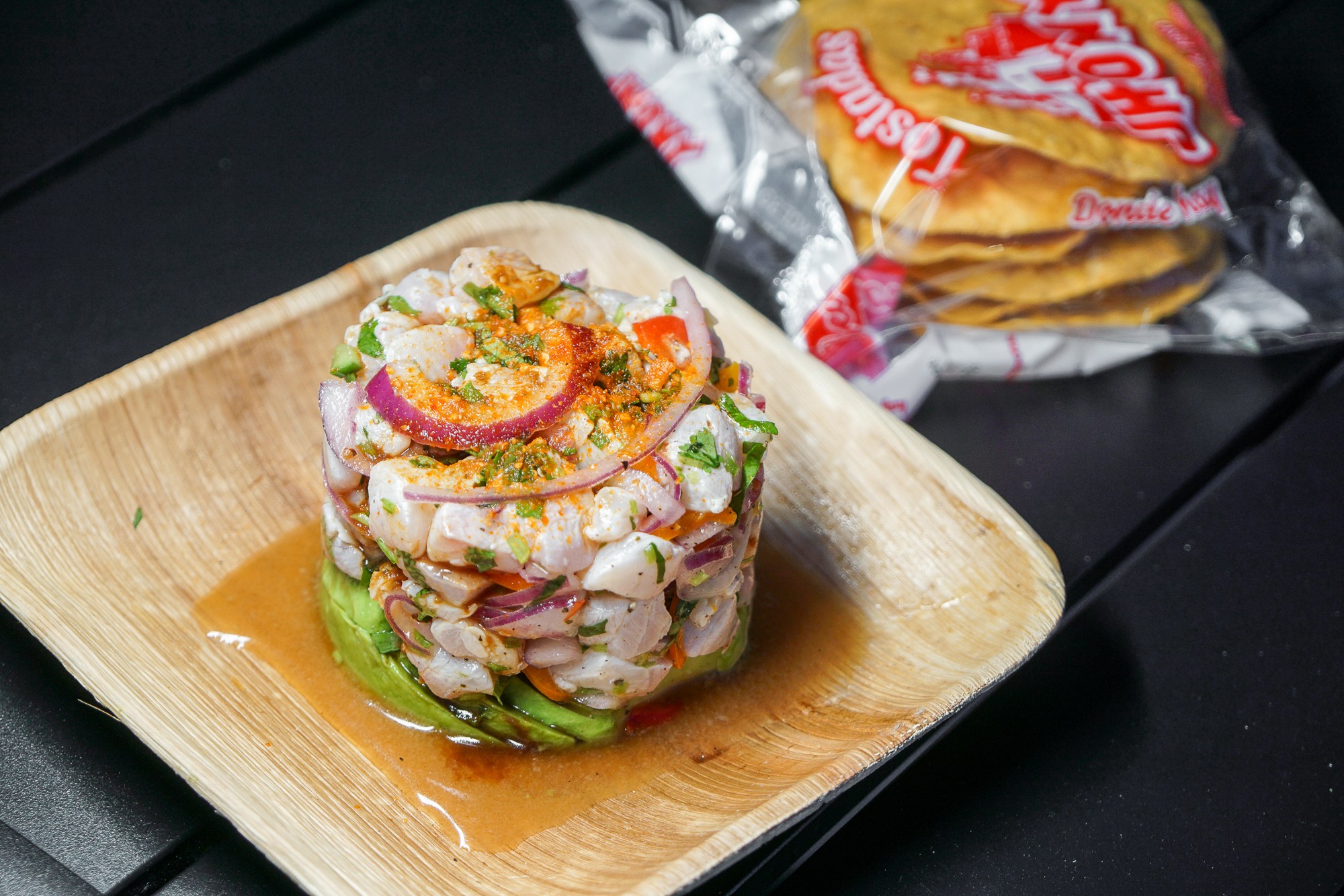 Mango habanero ceviche with tostadas from Del Mar Ostioneria on a faux wood plate.