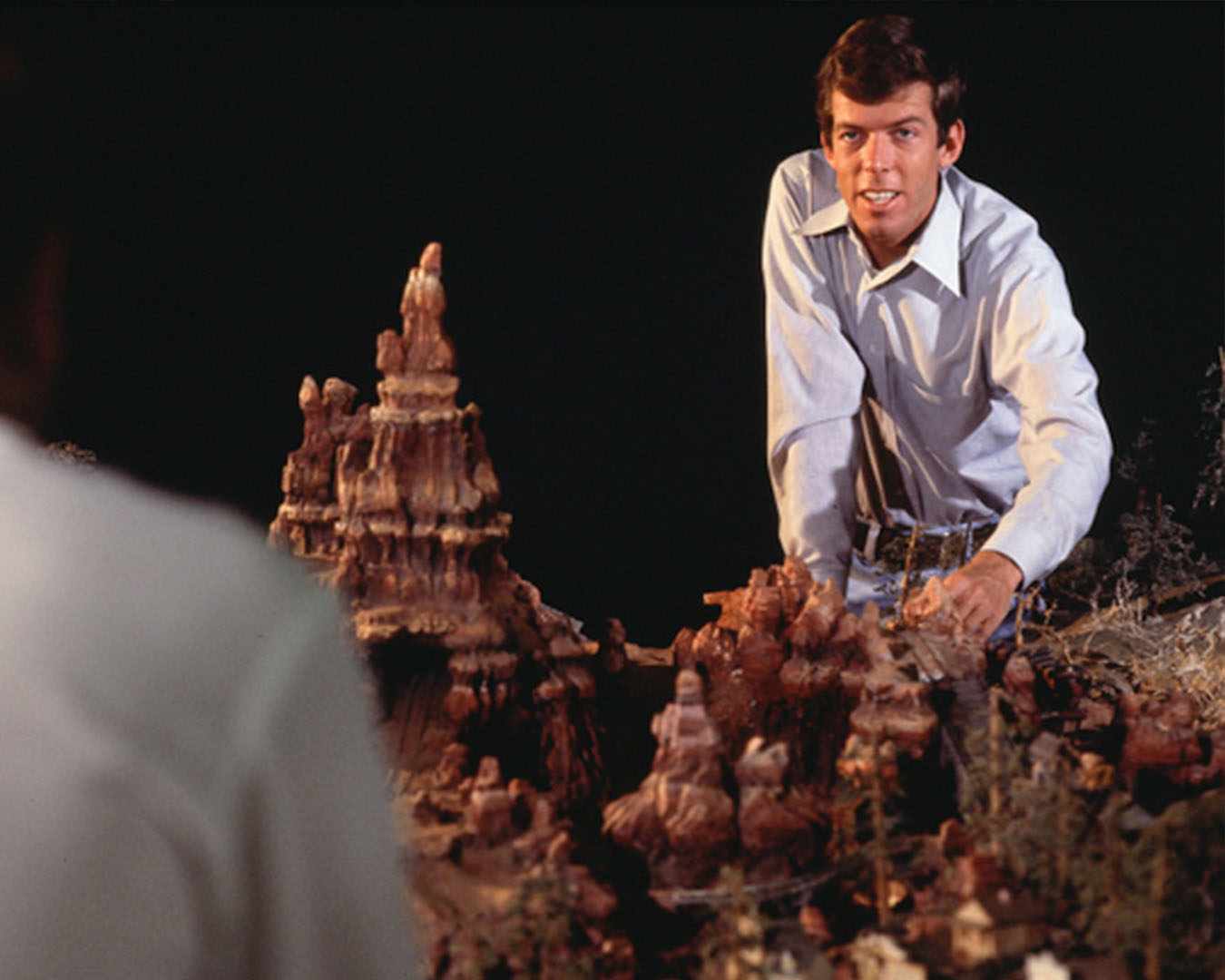 A person sits behind a model of a theme park ride