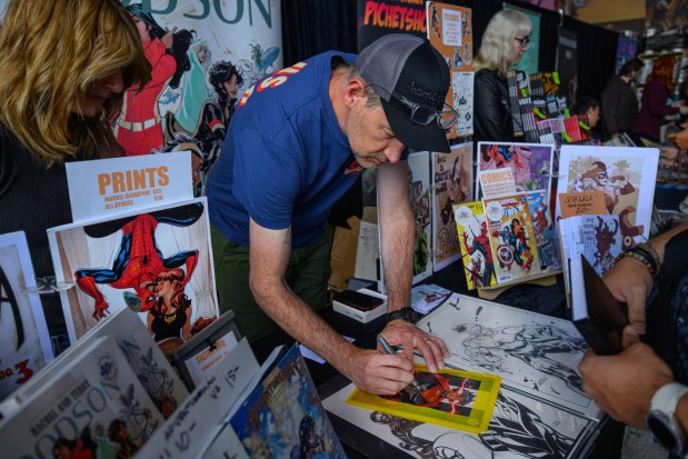 Comic book artist Terry Dodson autographs a comic book for a fan during the fourth annual Cape & Cowl Con held at Faction Brewing in Alameda, Calif., on Sunday, Aug. 30, 2026. The event is hosted by Oakland's Cape & Cowl Comics with 150 vendors, authors and artist attending. (Jose Carlos Fajardo/Bay Area News Group)