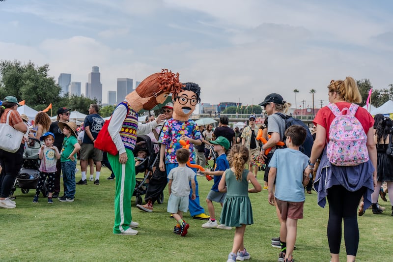 Attendees in papier-mâché heads interact with children.