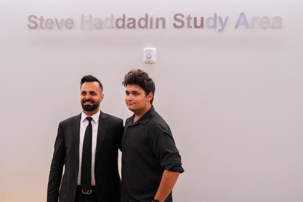 Two individuals stand together in front of a wall labeled “Steve Haddadin Study Area.”