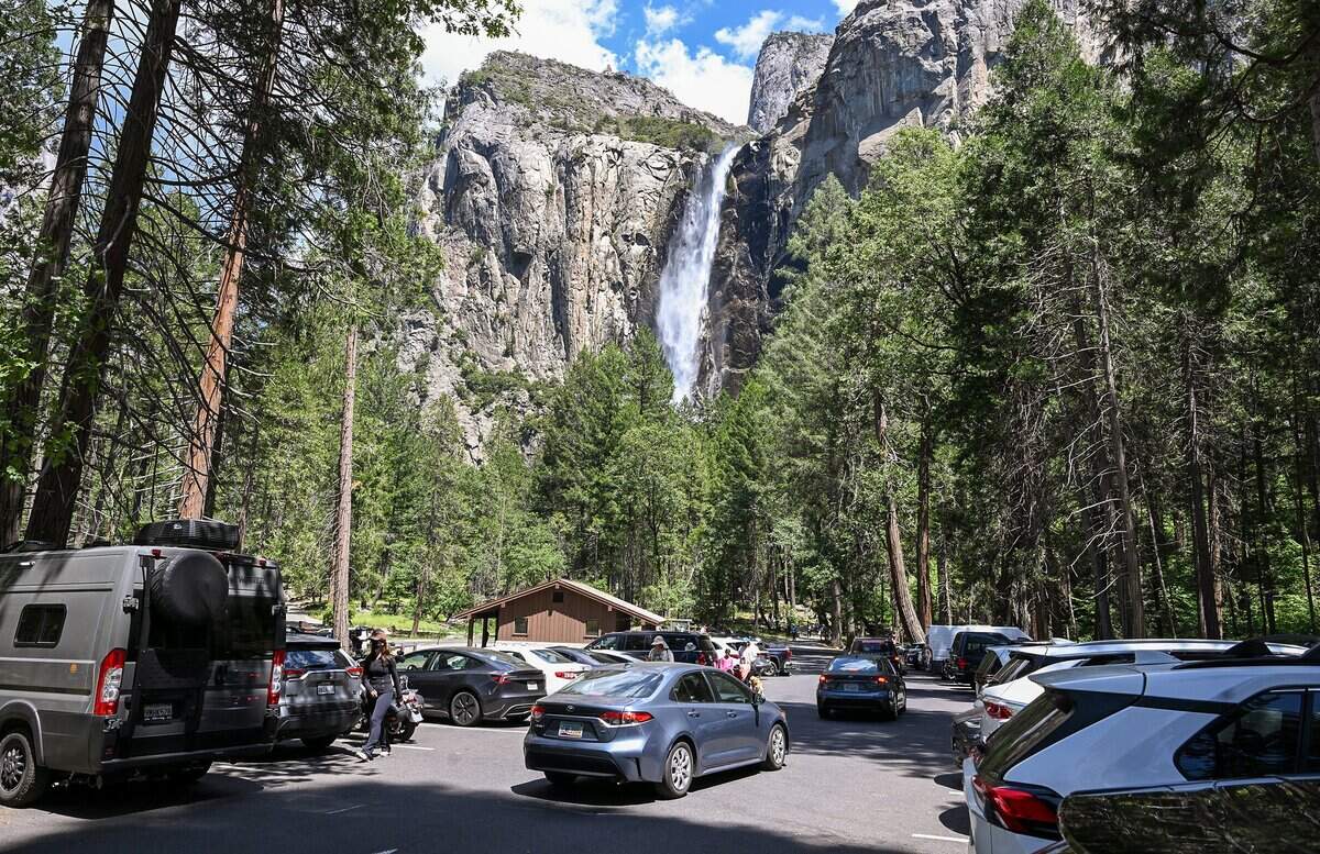 Water pours off of Bridalveil Fall as cars hunt for open parking stalls in the lot during a busy day at Yosemite National Park on Thursday, May 21, 2026.