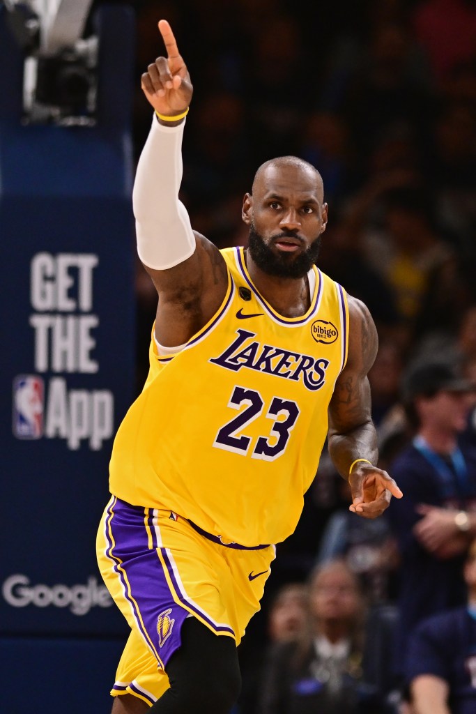 LeBron James in a Lakers uniform with his right arm raised, pointing his index finger upward.