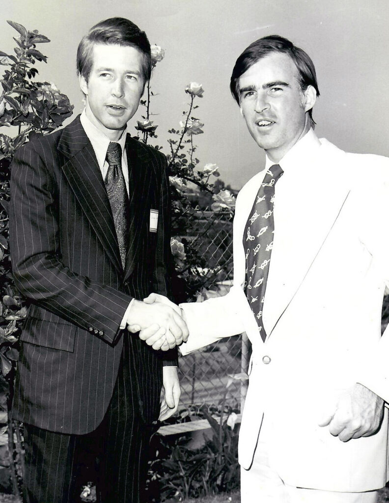 In a black and white photo, Grey Davis in a suit and tie shakes hands with Gov. Jerry Brown.