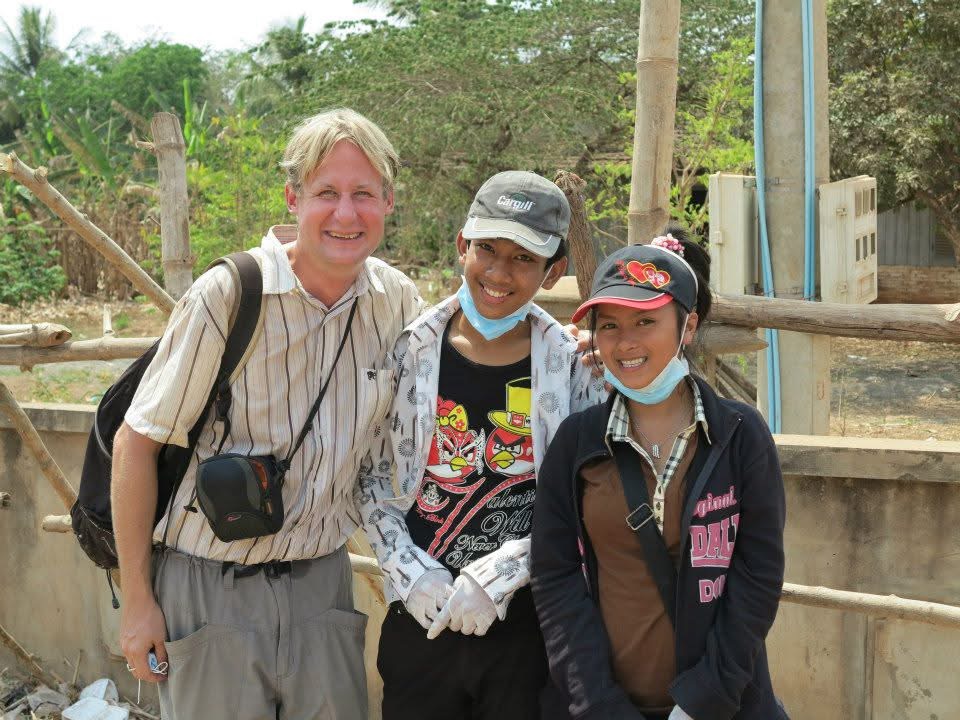 Greg Cera stands outdoors with two people during his Peace Corps service