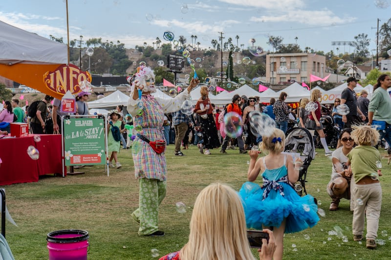 Festival attendee blows bubbles into a group of children.
