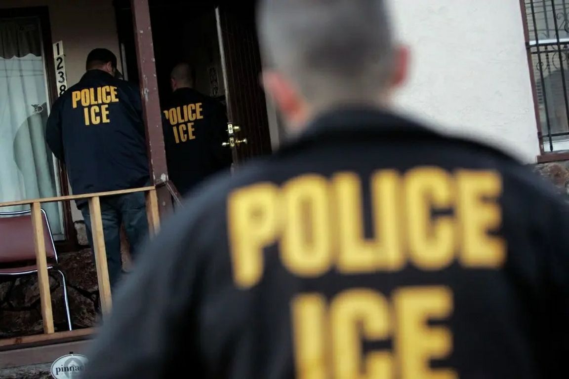 ICE agents wearing jackets marked “Police ICE” enter a home in Oakland.