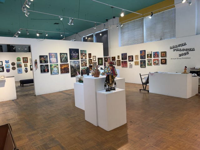 IMAGE_1 Wide view of the Laluzapalooza 2026 exhibition at La Luz de Jesus Gallery, featuring colorful artwork displayed across gallery walls and pedestals.