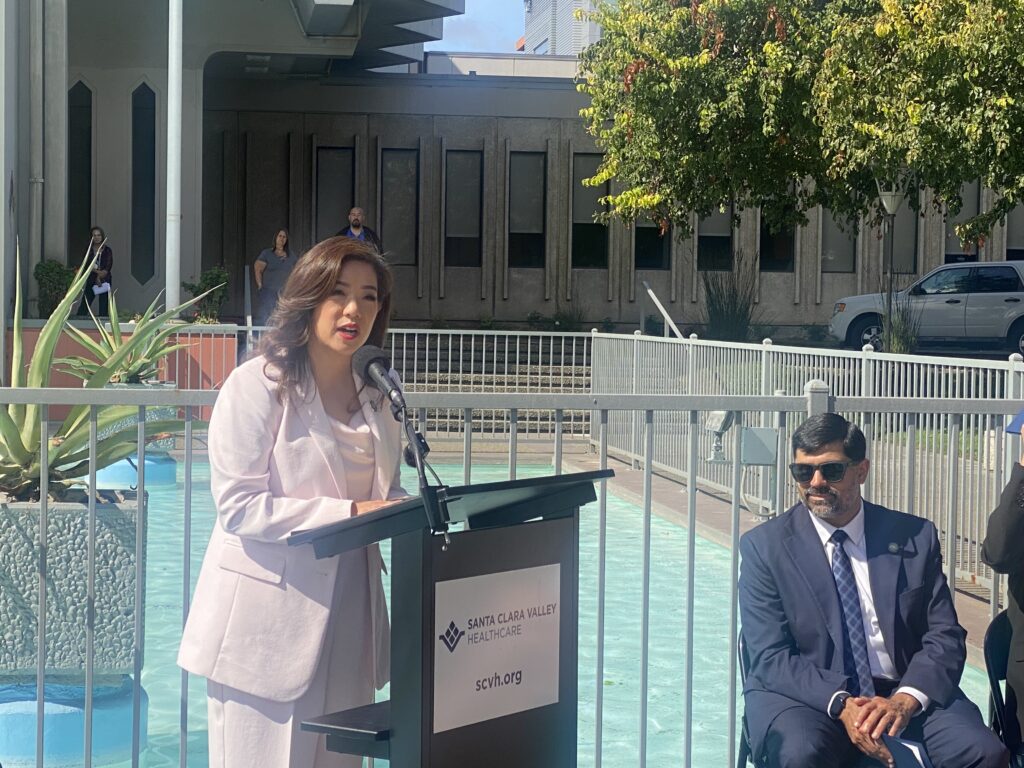 A woman speaking at a podium outside a hospital in San Jose, California