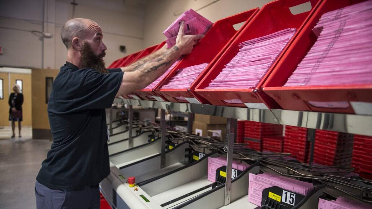 David Quiel, an elections assistant, works on a machine that processes vote by mail ballots at the Department of Voter Registration and Elections in Sacramento, Calif., on Thursday, May 17, 2018.